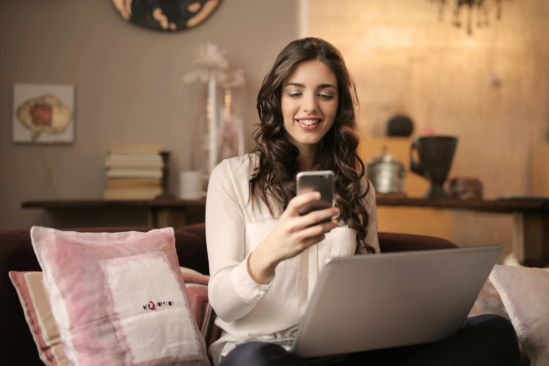 A parent checking their phone for camp waitlist updates on the sofa